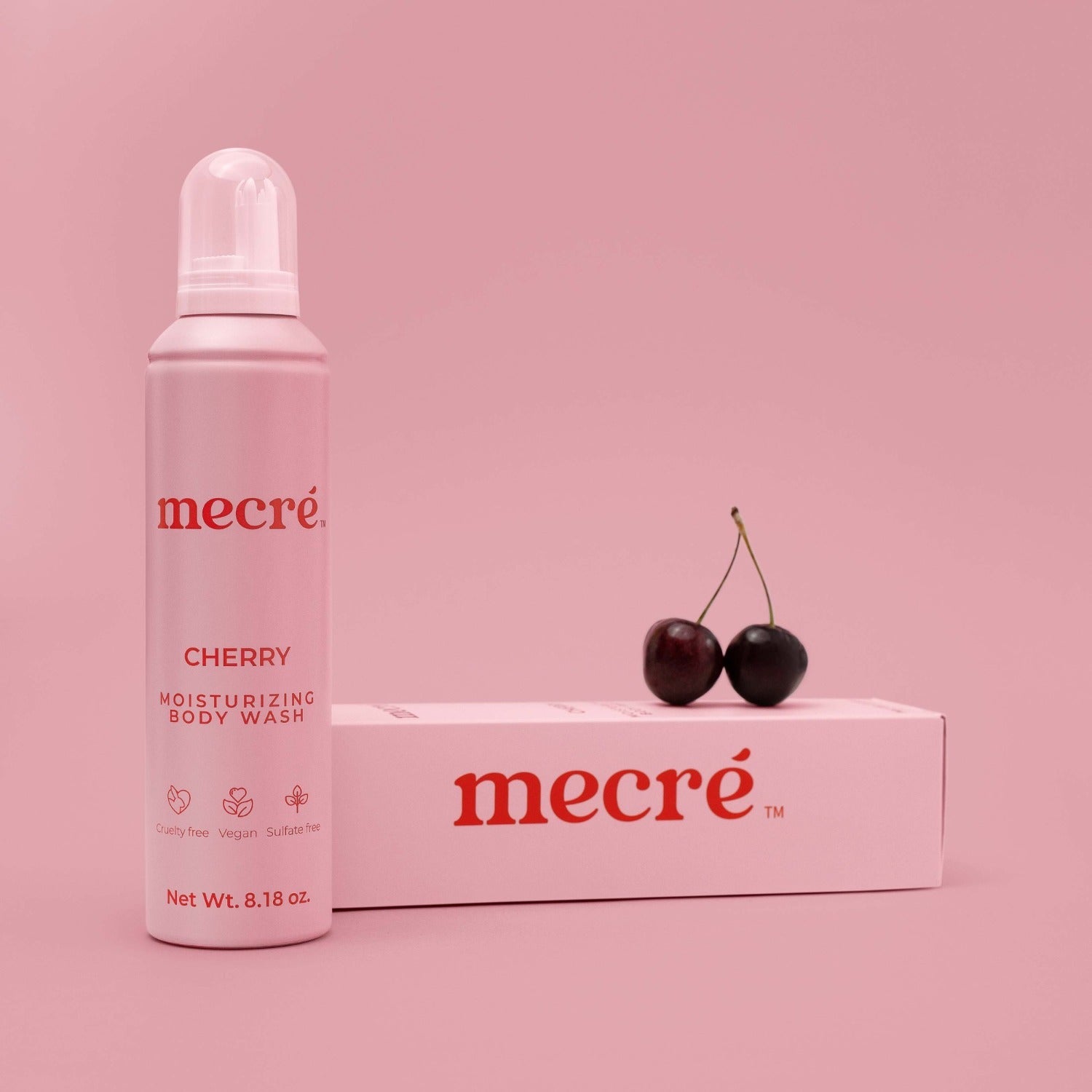Front view of Mecré moisturizing body wash in cherry scent, displayed with its packaging and two cherries.
