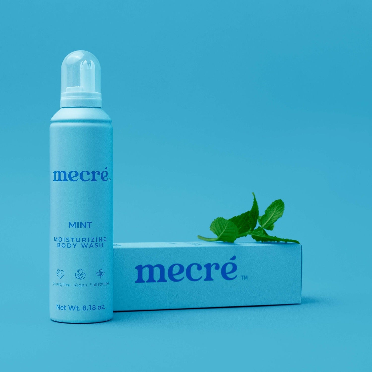 Front view of Mecré moisturizing body wash in mint scent, displayed with its packaging and a few mint leaves.